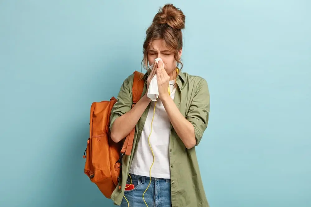 Allergist in 3071 Perry Ave, Bronx, NY 10467 — a young woman sneezes, showing allergy symptoms that require diagnosis and treatment.