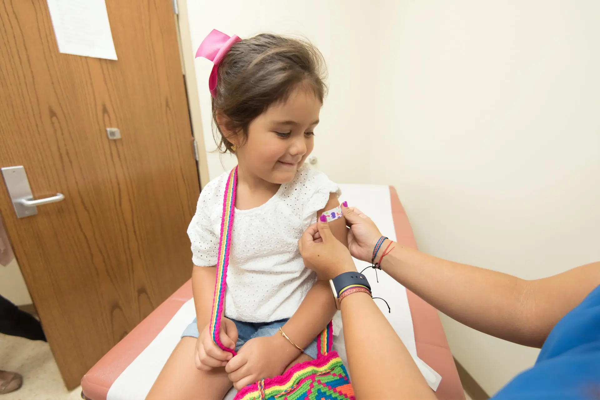 Pediatric care in 3071 Perry Ave, Bronx, NY 10467 — a smiling girl receives a bandage after a check-up, reflecting gentle and professional healthcare for children.